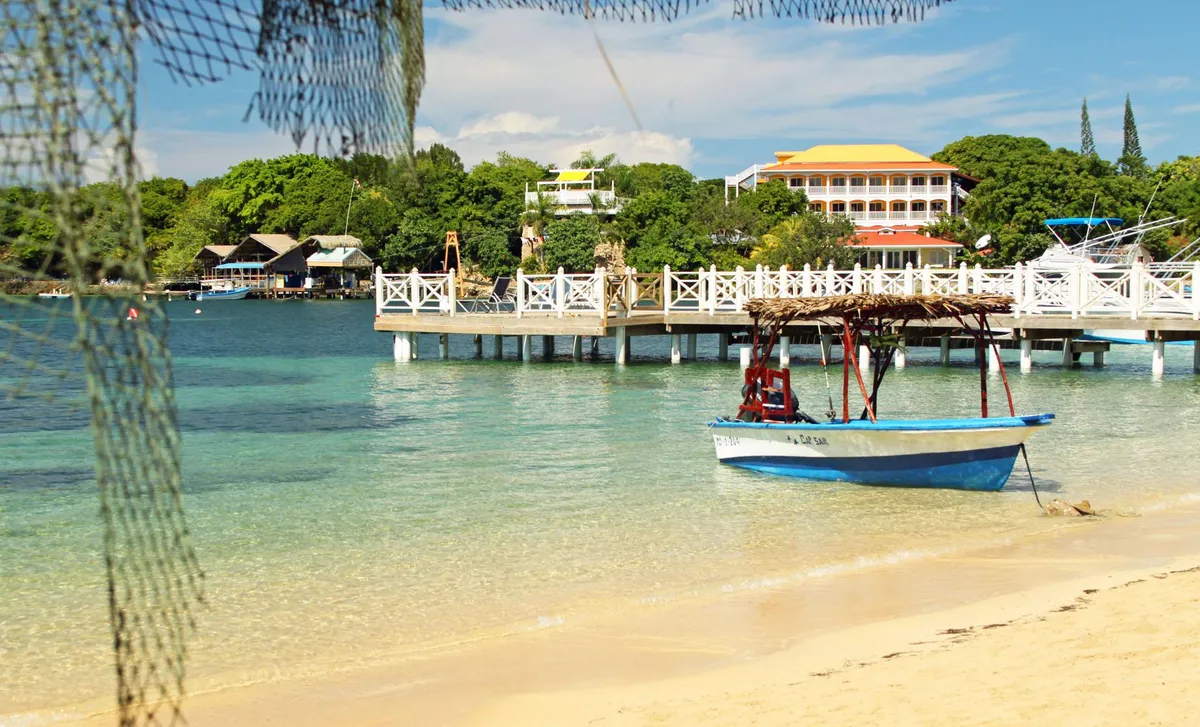 A calm West Bay beach with a boat, where the Roatan ATV and zip line adventure ends