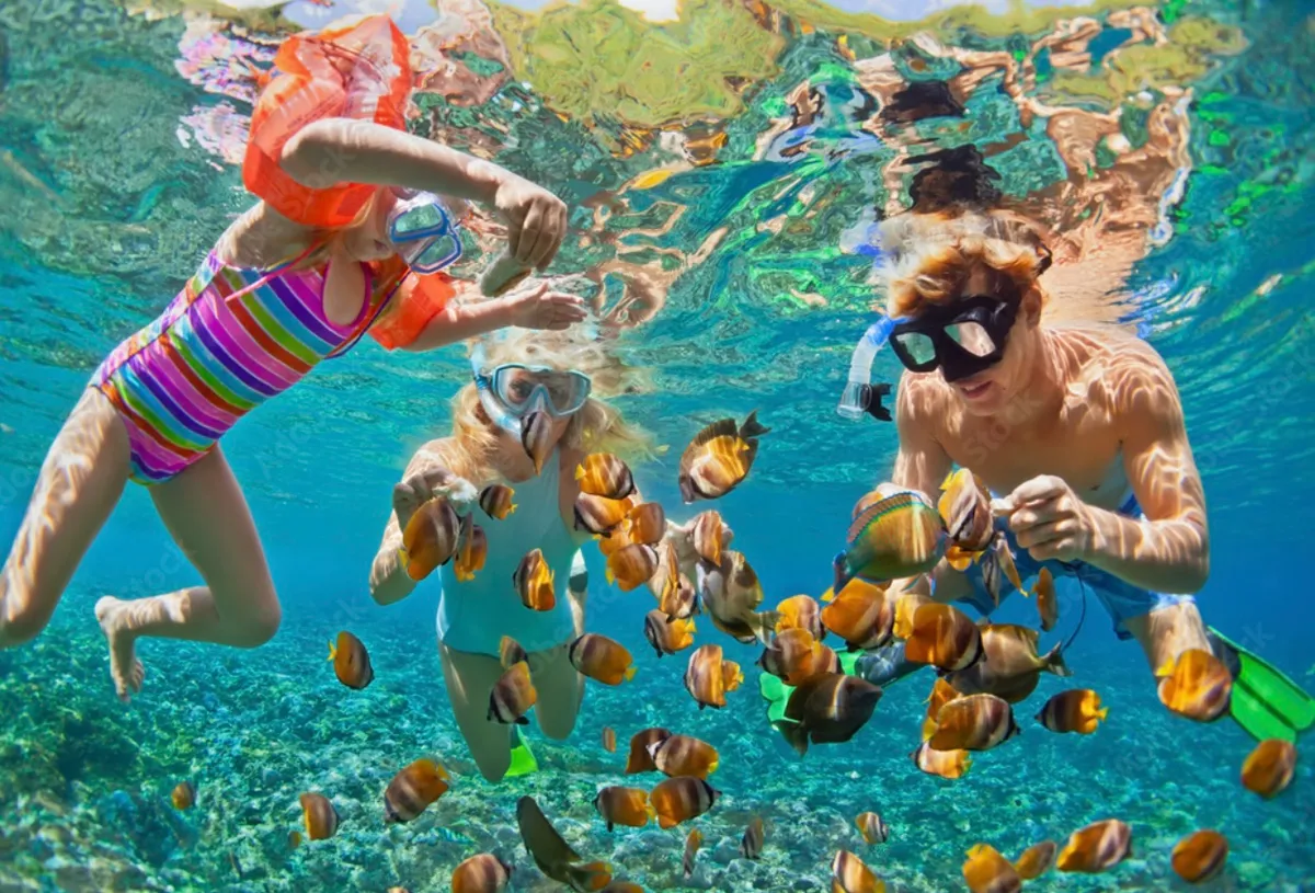 Children snorkeling among reef fish in the clear water at West Bay, Roatan